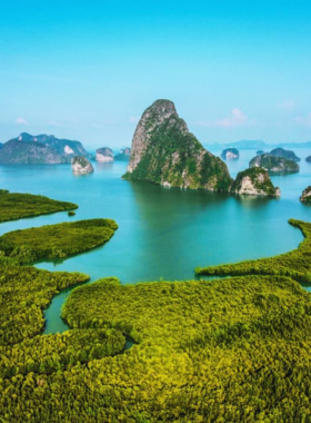 This image shows tourists exploring the stunning Phang Nga Bay, famous for its limestone cliffs and crystal-clear waters, perfect for island hopping and adventure.