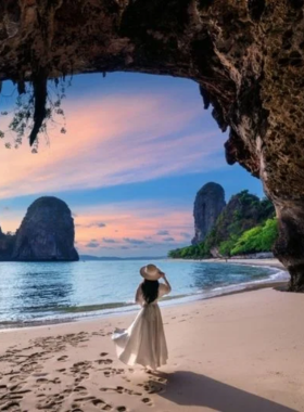 This image shows Railay Beach in Southern Thailand, with dramatic limestone cliffs framing the shoreline. The tranquil turquoise waters and the setting sun provide the perfect backdrop for beach and landscape photography.