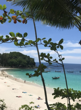 This image shows the serene Freedom Beach, surrounded by lush greenery and cliffs, offering a peaceful environment with no crowds. The clear blue water and soft sand create an ideal setting for relaxation, as a few people quietly enjoy the natural beauty of this hidden gem.