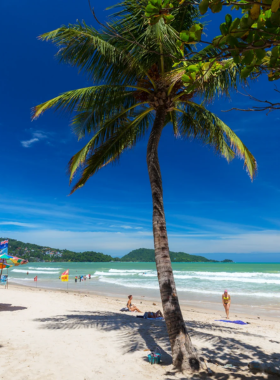 This image shows the lively Patong Beach in the evening, with vibrant lights illuminating the beach and people enjoying water sports. In the background, there are beach clubs and nightlife spots buzzing with activity, making it a perfect place for those seeking adventure and excitement.