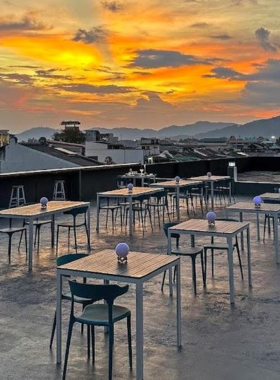 This image shows the scenic night view from Mystery Rooftop Bar in Phuket. It includes a beautifully lit open-air seating area, the city skyline in the background, and people enjoying drinks and conversations in a relaxed yet stylish setting.