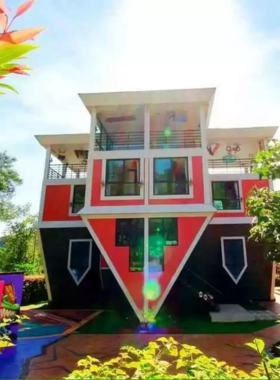 This image shows the quirky Baan Teelanka, an upside-down house in Phuket, offering a unique experience for visitors. The photo captures its inverted structure, with furniture hanging from the ceiling, creating an optical illusion that’s perfect for fun and creative photography.