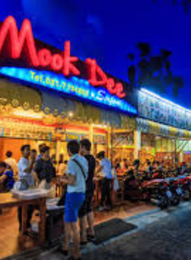 This image shows the bustling Rawai Seafood Market in Phuket, with vendors showcasing fresh seafood like prawns and lobsters. The vibrant market provides a lively experience for visitors, offering fresh catches cooked on-site by nearby restaurants for a delicious meal.