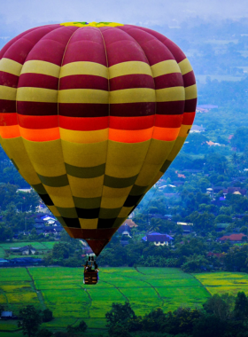 This image shows a hot air balloon rising above the lush landscape of Chiang Mai at sunrise. The breathtaking views of the city and surrounding countryside offer visitors a once-in-a-lifetime experience, making it a unique and serene way to enjoy the beauty of Chiang Mai from the sky.