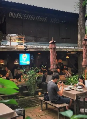 This image shows a platter of Northern Thai delicacies, including Sai Ua (spicy sausage) and Nam Prik Noom (green chili dip), served at Tong Tem Toh. The cozy restaurant ambiance enhances the cultural dining experience.