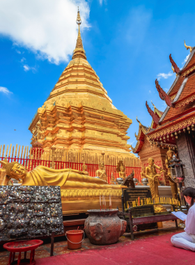 This image shows the breathtaking sunrise view from Doi Suthep temple, with the golden spire glowing in the morning light. The panorama includes the lush forest and cityscape below, bathed in soft, warm hues of dawn. The temple’s intricate golden details and peaceful ambiance reflect the spiritual significance of this site, making it an unforgettable experience for visitors.