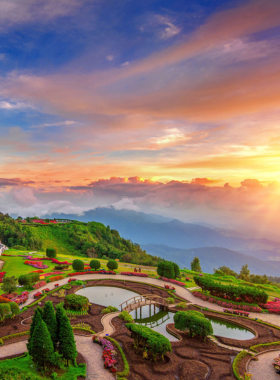 This image shows the stunning Wachirathan Waterfall at Doi Inthanon National Park, with water cascading down a rocky cliff surrounded by greenery. Visitors stand at a safe distance, taking photos and enjoying the refreshing mist. The vibrant colors of the lush forest and clear skies add to the scenic beauty of this natural wonder, making it a must-visit spot for nature lovers.