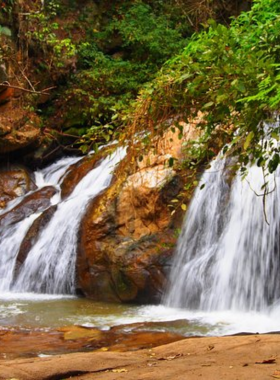 This image shows Mae Sa Waterfall, with its cascading water flowing over multiple tiers surrounded by lush green foliage. Visitors enjoy picnics by the stream, while others wade in the cool, clear waters. The serene and family-friendly environment makes it a perfect spot to relax and connect with nature. The natural beauty of the area is captured in every detail of the photo.