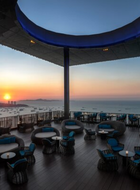 This image shows the panoramic city and sea views from Horizon Rooftop Restaurant & Bar at Hilton Pattaya. The setting includes chic open-air seating, perfect for sunset dining with fusion cuisine and cocktails.