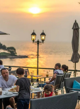 This image shows The Chocolate Factory’s artistic dessert display and cozy seaside seating. Visitors are indulging in handcrafted chocolates and savory dishes while enjoying picturesque ocean views.