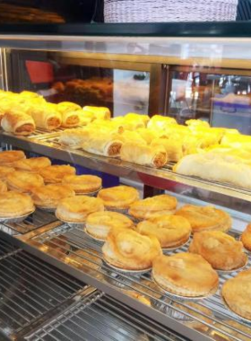 This image shows Tinnies Pies café, showcasing its freshly baked Australian-style meat pies, sausage rolls, and coffee. The cozy seating makes it an ideal stop for a comforting snack in Pattaya.