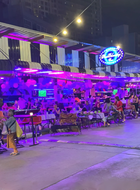 This image shows the vibrant food stalls at Soi Buakhao Night Market in Pattaya, offering a variety of Thai street food such as pad Thai, grilled seafood, and desserts. The lively ambiance is full of color and energy.