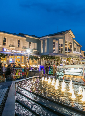 This image shows the variety of food stalls at Central Pattaya Market, offering dishes like fried chicken, spring rolls, and refreshing coconut ice cream. Visitors are enjoying the lively street food scene.