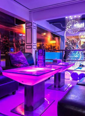 This image shows the frosty interior of V Lounge & Ice Bar in Pattaya, with ice-crafted furniture, colorful lights, and patrons enjoying unique cocktails in a sub-zero setting.