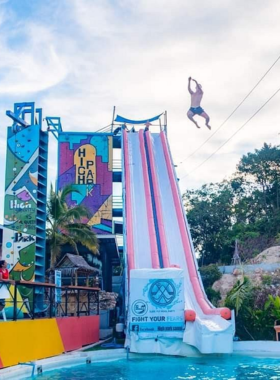 This image shows the adventurous High Park Samui, featuring water slides and zip lines amidst lush greenery, where visitors can enjoy an exciting day filled with fun activities, including foam parties and poolside relaxation.