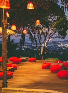 This image shows The Jungle Club, perched high in the hills of Koh Samui, offering a breathtaking panoramic view of the lush greenery and blue waters. It captures the tranquil ambiance, outdoor seating, and signature drinks and dishes served in this serene cafe.