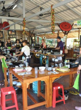 This image shows participants preparing traditional Thai dishes during a cooking class at Island Organics Samui. The hands-on experience teaches visitors to create authentic Thai meals using fresh, organic ingredients in a fun and educational atmosphere.