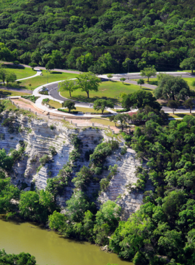 This image shows Cameron Park in Waco, Texas, featuring scenic hiking trails, lush greenery, and picnic spots. Visitors can be seen enjoying the outdoor spaces, while the Waco Sculpture Zoo adds artistic flair to the park’s atmosphere.