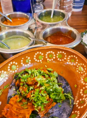 This image shows a small group of visitors enjoying a food tour in Puerto Vallarta, sampling local delicacies such as tacos and ceviche, and learning about the city's culinary traditions from a guide.