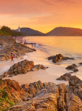 This image shows the beautiful beaches of Phuket, Thailand. Crystal-clear turquoise waters, golden sand, and vibrant beach activities attract tourists looking for both relaxation and adventure.