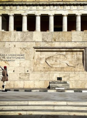 This image shows the Tomb of the Unknown Soldier, located near the Greek Parliament in Syntagma Square. The monument is dedicated to soldiers who lost their lives in wars. The ceremonial Changing of the Guard, conducted by elite soldiers known as Evzones, is a significant and traditional event held here.