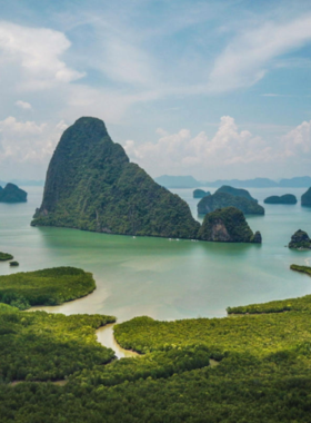 This image shows a boat tour in Phang Nga Bay, Thailand, with dramatic limestone cliffs rising above calm waters. Tourists can explore hidden caves, lagoons, and scenic islands in this breathtaking natural wonder.