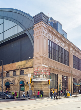 This image shows the bustling Reading Terminal Market in Philadelphia, where visitors can enjoy a variety of local and international foods, including the famous Philly cheesesteak, alongside fresh produce and artisanal crafts.