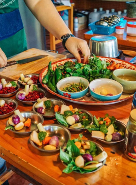 This image shows a group of people learning to cook traditional Thai dishes in a cooking class. The instructor demonstrates how to make popular dishes like Green Curry and Pad Thai, offering a hands-on experience of Thai cuisine.