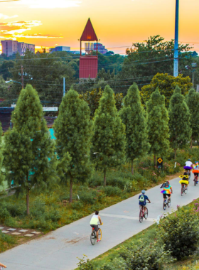 This image shows the Atlanta BeltLine, featuring a vibrant public trail with street art murals and visitors biking and walking. The scene captures the creative and community-driven atmosphere of this transformative urban project.