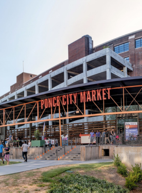 This image shows Ponce City Market in Atlanta, with its historic brick façade and trendy rooftop attractions. People are seen shopping and dining, showcasing the market’s blend of history and modern lifestyle offerings.