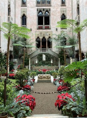 This image shows the Isabella Stewart Gardner Museum in Boston, designed like a Venetian palace with a lush courtyard filled with seasonal flowers. Visitors are seen admiring the architecture and priceless art collections housed within this unique cultural gem.