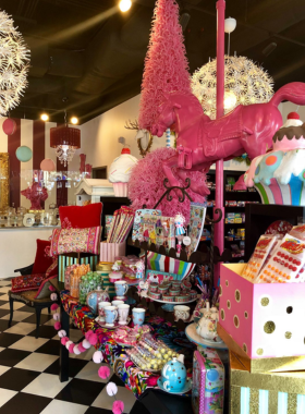 This image shows the interior of Pinkitzel Cupcake & Candy Shop, filled with colorful cupcakes and vibrant candy displays in a whimsical setting.