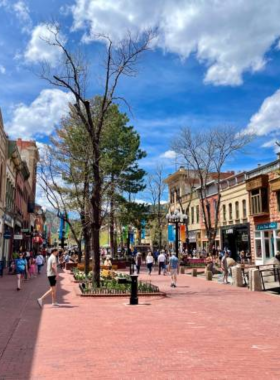 This image shows a vibrant Pearl Street Mall in Boulder, bustling with people shopping, dining, and enjoying live performances. The pedestrian-friendly area is filled with charming boutiques, cafes, and street art, showcasing the city's lively and creative atmosphere."