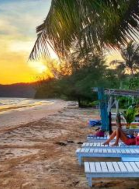 This image shows Sabai Beach, a hidden paradise reached after a jungle trek. The pristine sand and untouched natural beauty of the beach make it an ideal spot for relaxation. Visitors are picnicking under the shade of palm trees.