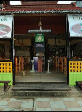 This image shows the cozy interior of Charlie and Leks restaurant in Pai, Thailand. The photo highlights the simple yet inviting atmosphere, with wooden tables and chairs set against a warm, homely backdrop. A bowl of traditional Khao Soi is served on the table, capturing the authentic flavors of northern Thai cuisine.