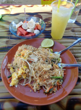 This image shows the authentic dining experience at Two Sisters Restaurant in Pai. The plate of vibrant Pad Thai served with lime and peanuts captures the essence of Thai home-cooked meals. The cozy, local-style setting adds to the charm of this eatery.