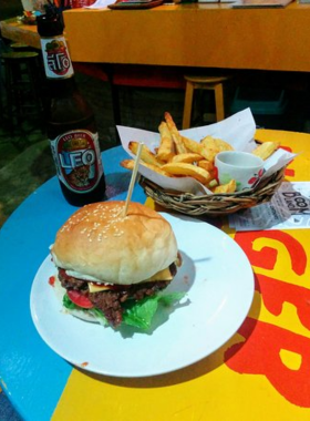 This image shows a juicy gourmet burger served at Maya Burger Queen in Pai, paired with crispy fries. The burger is topped with fresh lettuce, tomato, and melted cheese, showcasing the hearty Western-style meals offered at this cozy joint.