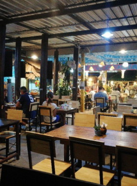 This image shows a beautifully plated pasta dish at THAM MA DA Cafe in Pai, featuring fresh herbs and creamy sauce. The rustic wooden table and lush greenery in the background reflect the farm-to-table philosophy of the cafe.