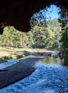 This image shows the entrance to Tham Lod Cave in Pai, Thailand, where bamboo rafts glide through the cave's interior, revealing fascinating rock formations and a mystical atmosphere.