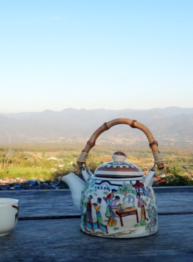 This image shows the quirky giant teapot in Pai, Thailand, set against a scenic backdrop of mountains and greenery. The whimsical design makes it a unique and playful photo opportunity for visitors.