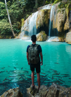 This image shows a scenic hike through lush forests on the way to Erawan Falls, a beautiful multi-tiered waterfall located outside of Ayutthaya. Hikers enjoy breathtaking views of streams, natural landscapes, and the refreshing pools of the waterfall. The trail is moderate in difficulty, leading to a stunning reward at the end. The image captures the serenity and beauty of Thailand’s natural environment, making it an unforgettable experience for nature lovers and hiking enthusiasts.