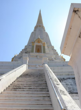 This image shows Wat Phu Khao Thong, or Golden Mount, with its towering stupa surrounded by peaceful countryside. The steps leading to the top offer panoramic views of rice fields and villages.