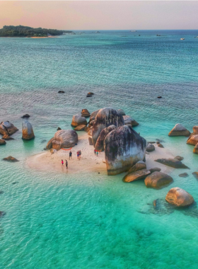 This image shows the iconic granite boulders scattered along the shoreline of Belitung Island in Sumatra, Indonesia. The turquoise waters and soft sandy beach create a peaceful and picturesque scene. The image emphasizes the island's unspoiled beauty and unique landscapes, making it an ideal destination for beach lovers and photographers.
