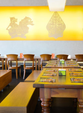 This image shows a platter of satay skewers served with a rich peanut sauce at Sate Khas Senayan in Jakarta. The dish is presented alongside rice cakes and traditional condiments. The image captures the essence of authentic Indonesian cuisine, highlighting the restaurant’s focus on flavor and tradition. The cozy dining space in the background adds to the inviting atmosphere for family or casual gatherings.