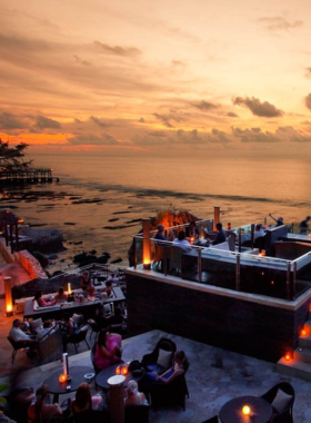 This image shows Rock Bar in Jimbaran perched on a cliffside, offering breathtaking views of the Indian Ocean. Guests can enjoy cocktails while watching the stunning sunset. The minimalist design and live acoustic performances create a romantic yet lively atmosphere.