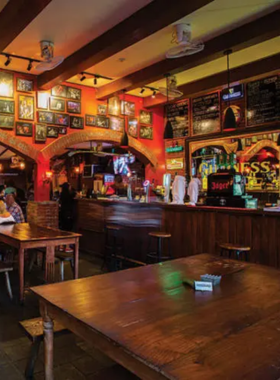 This image shows The Orchard Bar & Restaurant in Bali, with a live music performance taking place. The cozy setting includes wooden furniture, soft lighting, and an engaged audience enjoying soulful tunes over drinks and food.