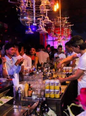 This image shows Bali Joe Bar, a vibrant LGBTQ+ friendly bar in Bali. The scene captures colorful drag performances, a lively crowd cheering, and bartenders serving creative cocktails in an inclusive and celebratory atmosphere.