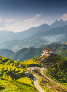 This image shows the stunning terraced rice fields of Muong Hoa Valley in Sapa, with vibrant green steps stretching into the misty mountains. A small local village is visible in the background, illustrating the harmonious blend of natural beauty and traditional Vietnamese culture.