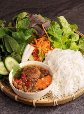 This image shows the signature dish of Bún Chả 145, featuring a plate of grilled pork served with vermicelli noodles, fresh herbs, and tangy dipping sauce. The vibrant colors of the ingredients create a visually appealing and appetizing presentation that represents authentic Northern Vietnamese cuisine.