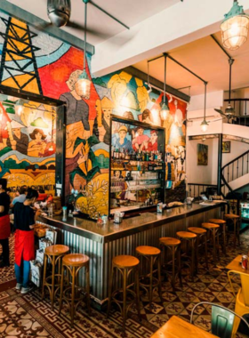 This image shows the vibrant interior of Propaganda Bistro, adorned with colorful wall art and modern decor. The dishes on display include fresh spring rolls, banh xeo, and a refreshing cocktail, showcasing a creative twist on traditional Vietnamese cuisine.